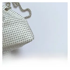 Gros plan des strass étincelants et de la chaîne en argent sur le sac seau blanc