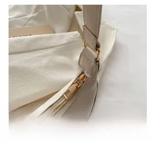 Detailed close-up of the smooth golden zipper and cream PU leather on the crescent bag