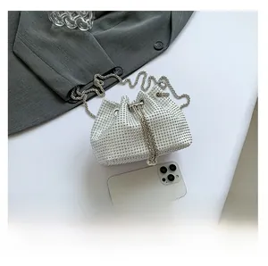 Mini sac seau à strass blancs avec chaîne argentée et perles à côté d'un smartphone