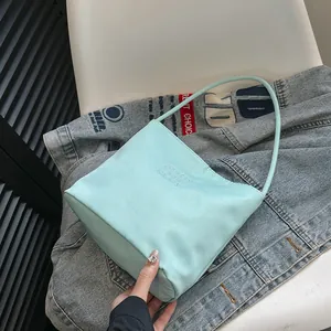 Fashionable mint green nylon shoulder bag with embroidery on casual denim background