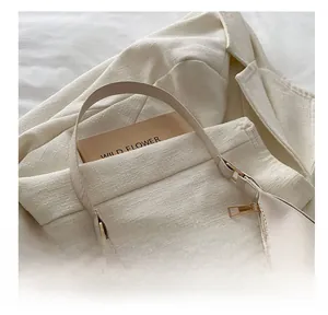 Detailed close-up of cream white handbag with golden clover metal buckle and textured strap