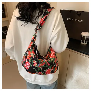 Dettaglio borsa a mezzaluna in nylon con vivace motivo a peonie indossata da modella