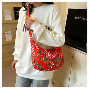 Dettaglio della borsa a tracolla in nylon rosso con motivo floreale cinese sul modello