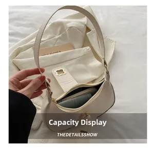 Capacity display of cream crescent bag showing space for phone and wallet with gold buckle