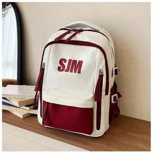 Detail eines rot-cremefarbenen Rucksacks mit SJM-Buchstabendruck und Mehrfachtaschen-Layout
