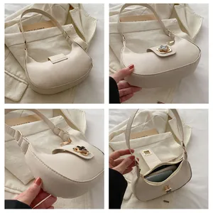 Detail view of cream crescent bag with gold clover clasp and zip closure