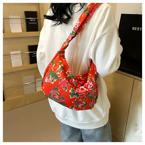 Dettaglio della borsa a mezzaluna in nylon rosso a tracolla con motivo floreale classico