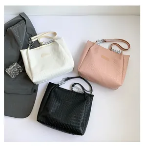 Detailed view of woven tote bags in white, pink and black with fashion metal chain straps