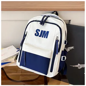 Detail des blauen SJM-Buchstabenaufdrucks auf cremefarbenem Rucksack mit Seitentasche