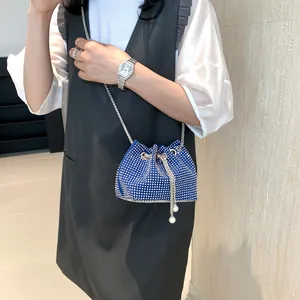 Sac seau bleu avec strass, chaînes argentées et détails en perles porté par un mannequin