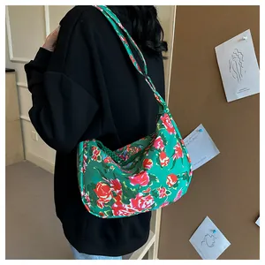 Dettaglio borsa hobo in nylon verde con motivo floreale rosso e tracolla larga