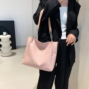Pink woven tote bag with silver chain strap shown on model in black suit for women