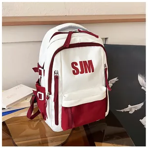 Detail eines rot-weißen Canvas-Rucksacks mit SJM-Buchstabendruck und verstärkten Gurten