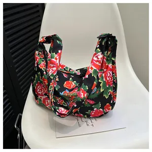 Dettaglio borsa in nylon con stampe floreali rosse e chiusura a cerniera nera