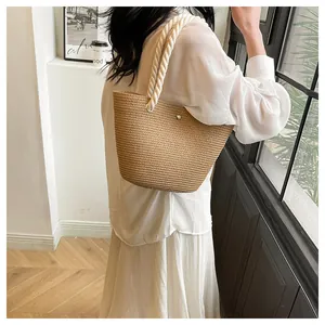 Détail du sac cabas en paille tissée avec poignées en corde blanche et œillets en métal