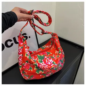 Dettaglio della borsa a mezzaluna in nylon rosso con fiori e tracolla regolabile