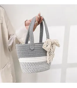 Detail of woven cotton tote bag with gray and white texture and beige lace bow accessory