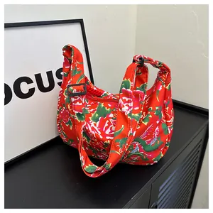 Dettaglio della borsa in nylon rosso con motivo floreale di peonie e tracolla regolabile