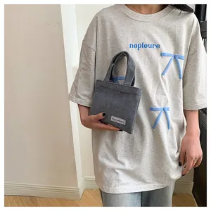 Detail der dunkelgrauen Cord-Mini-Tasche mit weicher Rippstruktur und Markenetikett