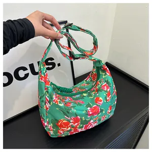 Dettaglio borsa hobo in nylon verde con tracolla regolabile e motivo floreale rosso