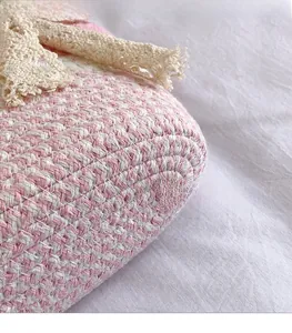 Close-up of pink and white woven cotton fabric with beige lace trim and soft texture