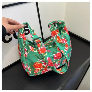 Dettaglio della borsa a tracolla in nylon verde con fiori rossi e tracolla regolabile