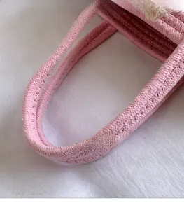 Detail of a pink woven handbag showing the sturdy braided cotton rope handle design