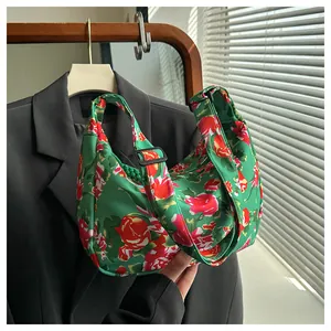 Dettaglio borsa a mezzaluna in nylon verde a fiori con tracolla larga e fibbia nera