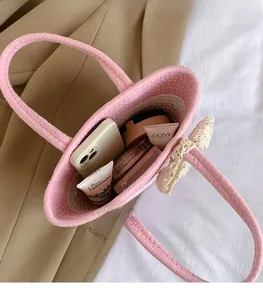 Pink woven straw tote bag with lace bow showing interior storage for phone and makeup