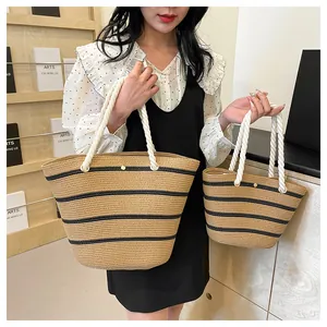 Détail de sacs cabas en paille tissée avec rayures noires et anses en corde en deux tailles