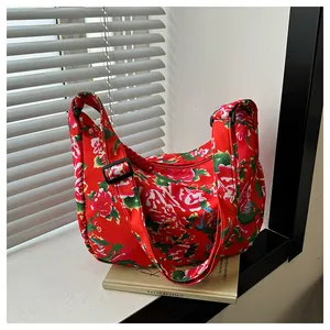 Dettaglio borsa in nylon a fiori rossi con tracolla nera regolabile e zip metallica