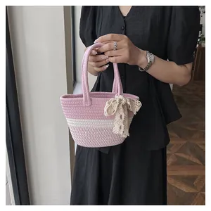 Close-up of pink and white striped woven bag with a delicate lace bow and twin handles
