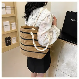 Vue détaillée d'un grand sac fourre-tout en paille rayé avec poignées en corde.