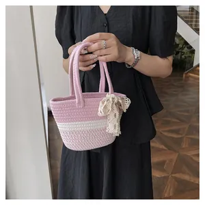 Detail of pink and white striped woven tote bag with lace bow accessory for summer