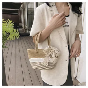 Close-up of handmade straw tote bag with elegant beige lace bow and woven handles