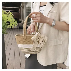 Close-up of woven straw handbag featuring a white lace bow detail and dual handles
