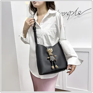 Détail d'un sac seau en cuir noir orné d'un pendentif en peluche lapin à carreaux chic