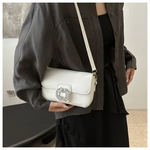 Detail of white mini square bag with crystal rhinestone buckle on shoulder strap