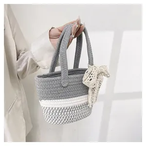 Detail of hand-woven bucket bag with grey houndstooth pattern and lace bow decoration