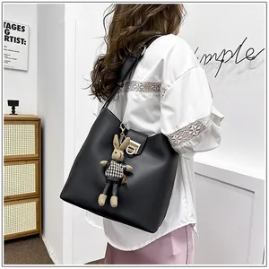 Détail d'un sac seau noir en cuir avec boucle dorée et breloque lapin mignonne