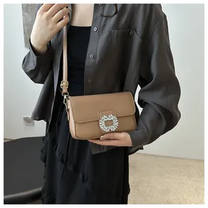 Close-up of square rhinestone buckle on camel leather small square crossbody bag