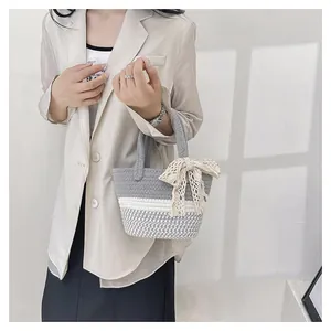 Detail of grey and white woven cotton handbag with a decorative beige lace bow