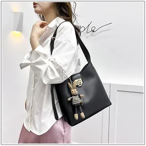 Détail du sac seau en cuir noir avec boucle dorée et breloque lapin mignonne attachée