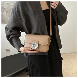 Minimalist beige crossbody bag with a square rhinestone buckle and leather strap
