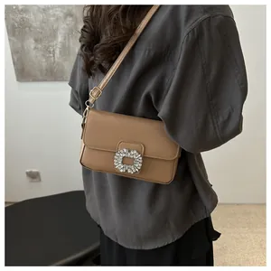 Detail of khaki textured leather shoulder bag with a sparkling rhinestone rectangle buckle