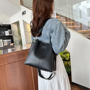 Minimalistische schwarze Beuteltasche mit gewebtem Riemen an der Schulter des Models