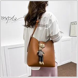 Sac seau en cuir marron avec breloque lapin et fermoir en métal porté par un mannequin