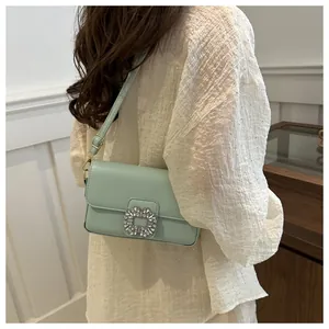 Detail shot of a mint green crossbody bag featuring a sparkling crystal buckle on the shoulder