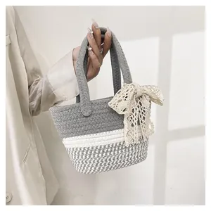 Detail of hand-woven basket bag featuring a delicate lace bow and gray textured pattern