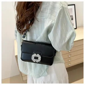 Close-up of elegant black crossbody bag with large crystal buckle and gold hardware